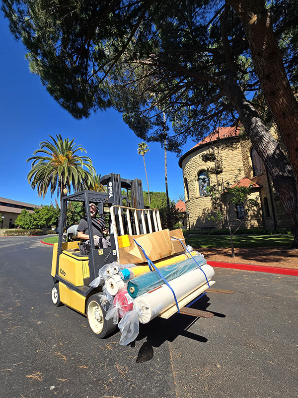 Craig driving the forklift of fabric to the Makerspace